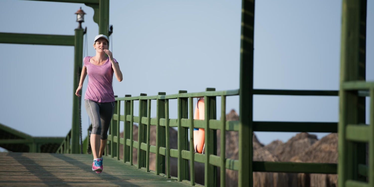 woman running virtual race outdoors over a bridge